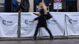 Eine Frau geht an einem Absperrung mit dem Logo der Münchner Sicherheitskonferenz vorbei.