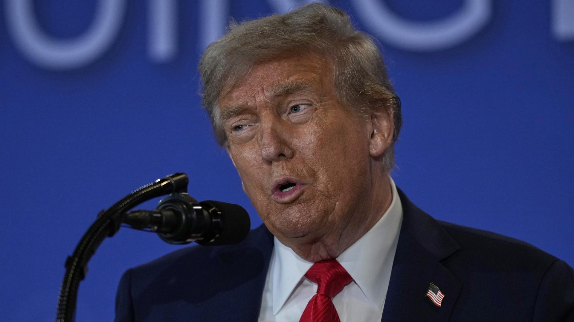 Donald Trump spricht in ein Mikrofon. | dpa