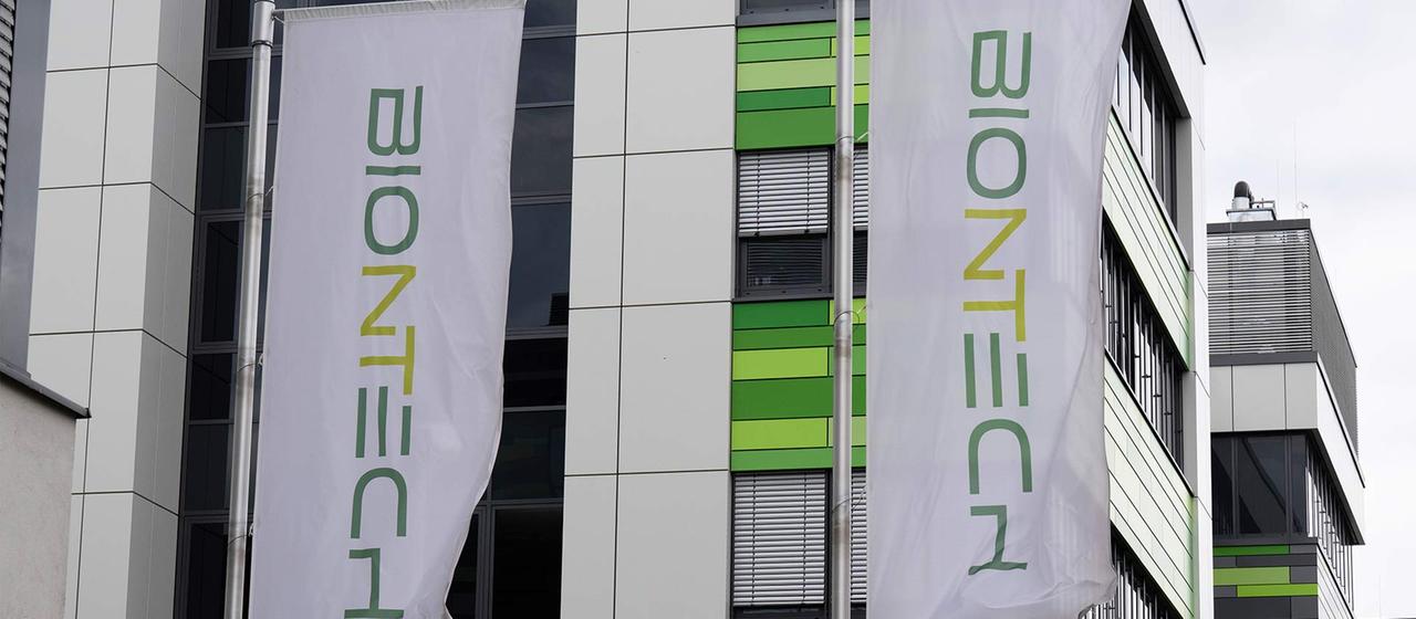 Fahnen mit dem Unternehmenslogo vor einem Laborgebäude von Biontech.