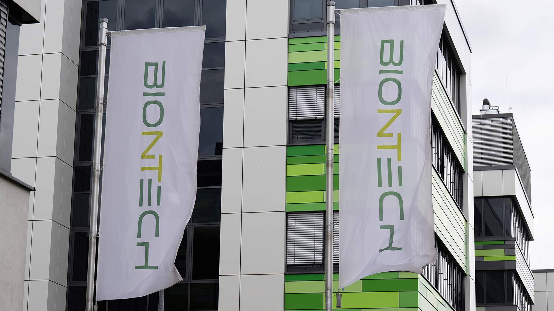 Fahnen mit dem Unternehmenslogo vor einem Laborgebäude von Biontech. | picture alliance/dpa