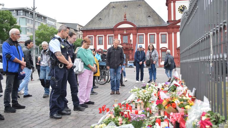 Mannheim: Zahlreiche Personen, darunter Polizisten, stehen in unmittelbarer Nähe des Tatorts vor niedergelegten Kerzen und Blumen.