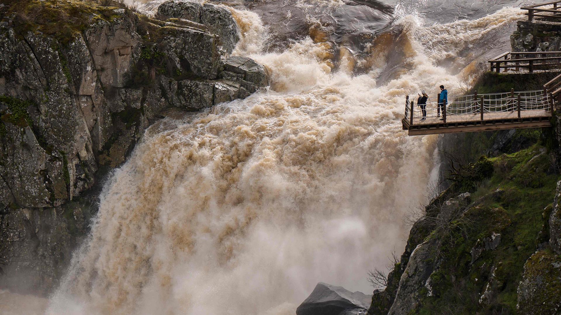 Menschen stehen auf einer Aussichtsplattform neben einem tosenden Wasserfall. | AFP