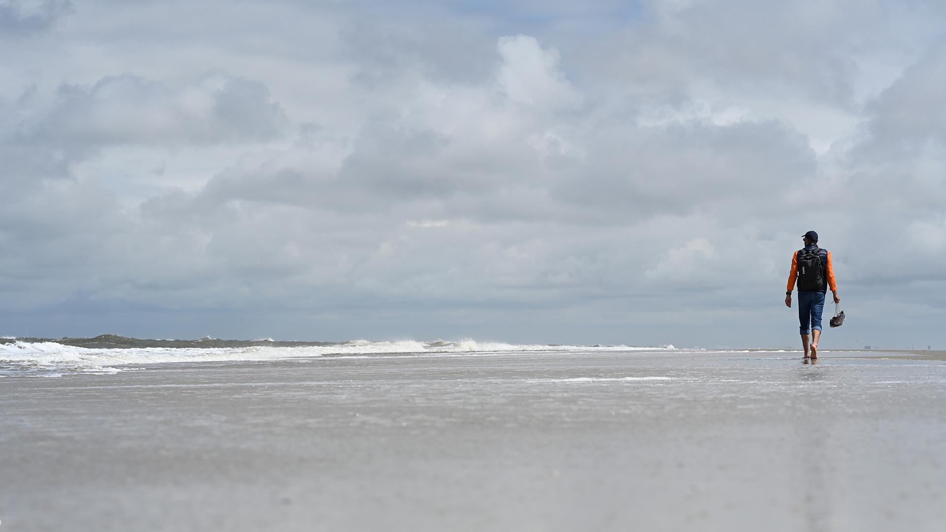 Ein Mann geht am Strand spazieren.