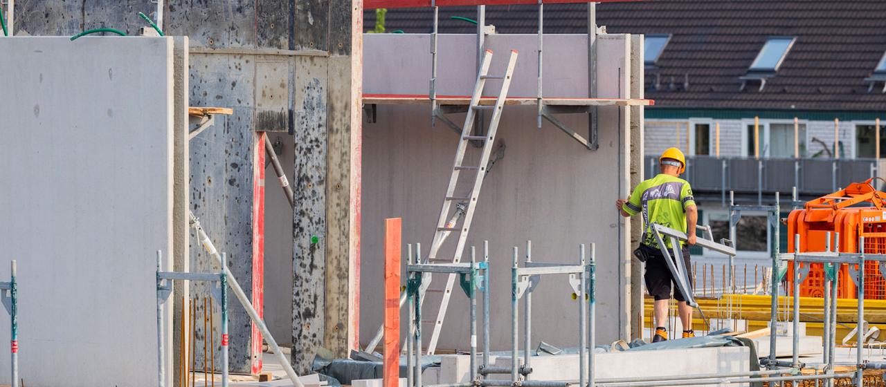 Bauarbeiter arbeiten an einem Rohbau für Eigentumswohnungen.