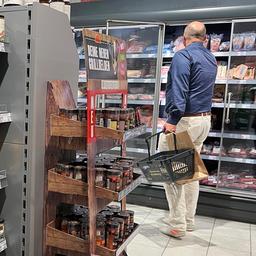 Ein Mann steht vor einem Kühlregal in einem Supermarkt.