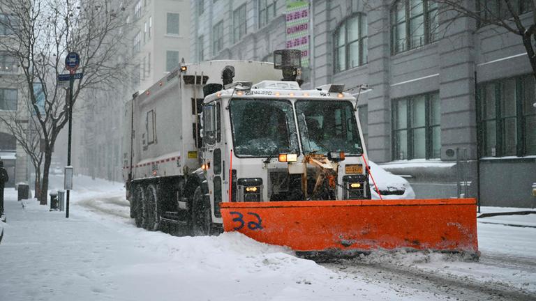 Ein Schneepflug räumt eine schneebedeckte Straße im New Yorker Stadtteil Brooklyn.