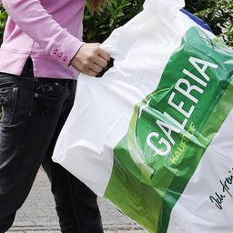 Eine Frau hält eine Karstadt- und eine Kaufhof-Einkaufstüte in den Händen.