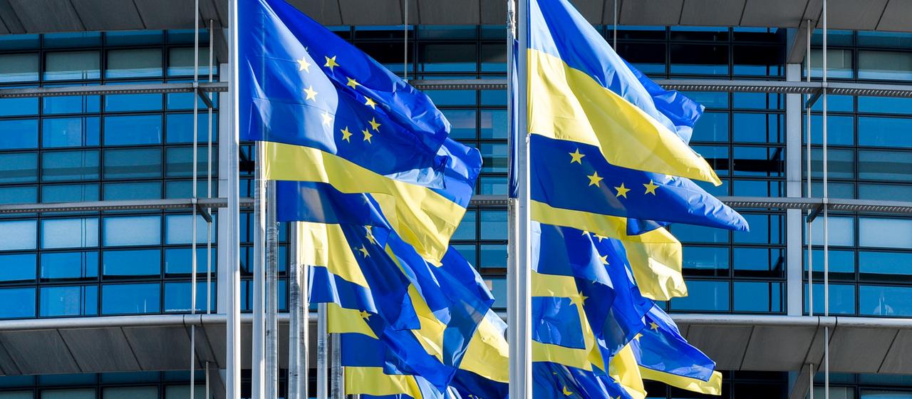 Europäische und ukrainische Flaggen wehen vor dem Europäischen Parlament.