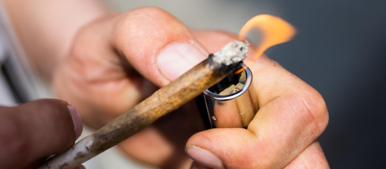 Ein Mann zündet sich einen Joint an.