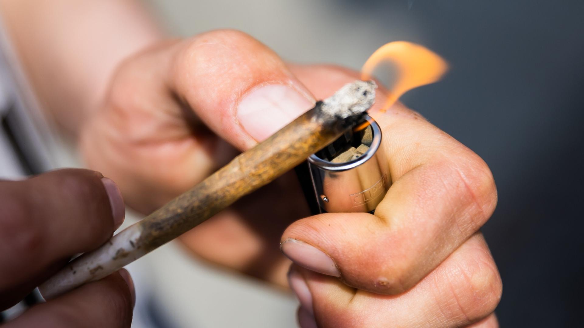 Ein Mann zündet sich einen Joint an. | picture alliance/dpa
