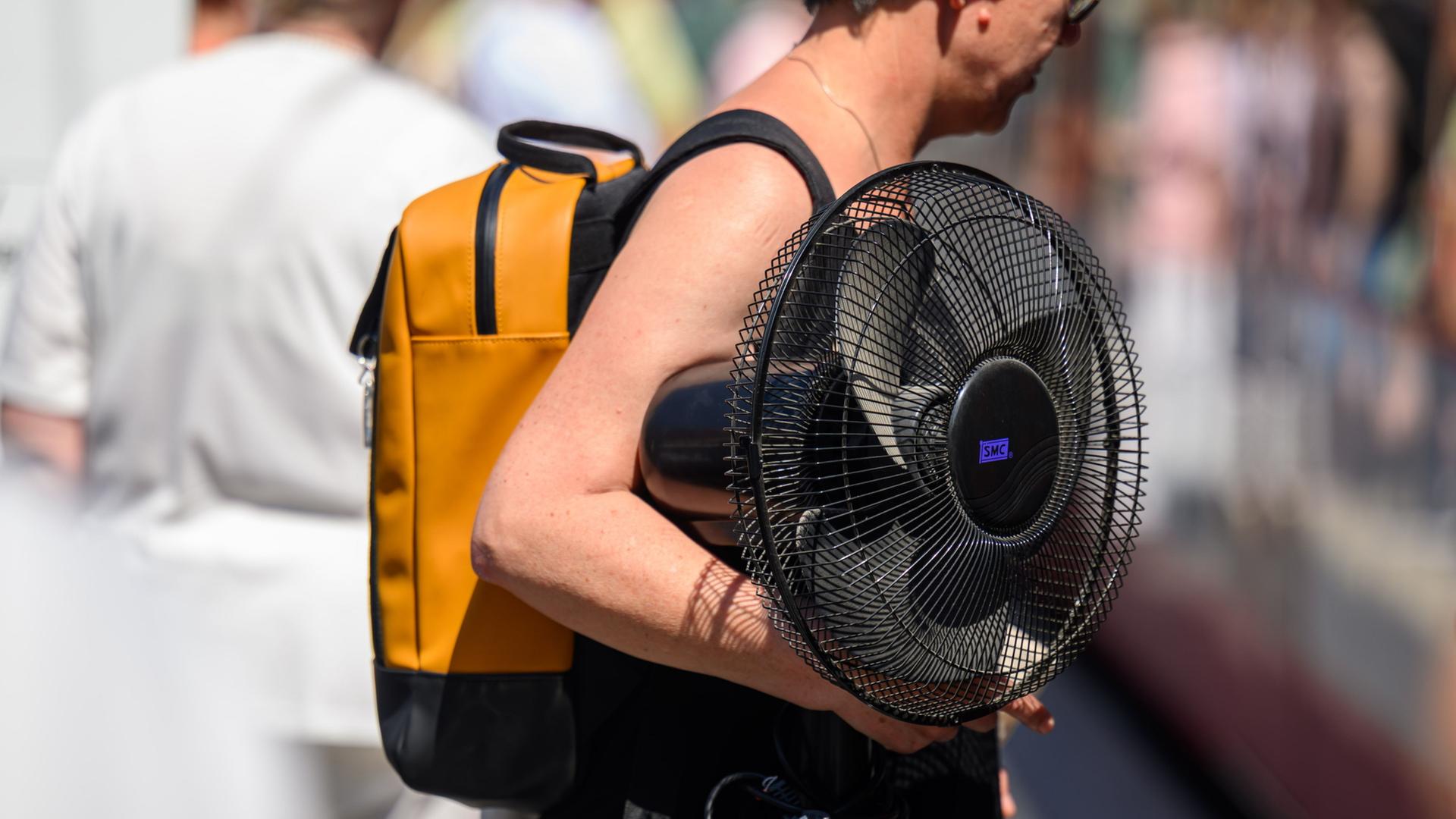 Eine Frau trägt am Markt in Halle/Saale einen Ventilator unter ihrem Arm.  | Hendrik Schmidt/dpa
