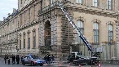Polizisten stehen neben einem Lastenaufzug am Louvre-Museum.