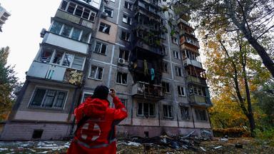 Ein Mitarbeiter des Roten Kreuzes steht vor einem durch einen Drohnenangriff beschädigten Gebäude in Kiew