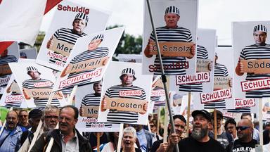 Auf Plakaten, die bei einer Anti-Corona-Demo in Berlin hochgehalten werden, sind Politiker und der Virologe Drosten abgedruckt.