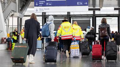 Menschen mit Koffern laufen durch eine Bahnhofshalle