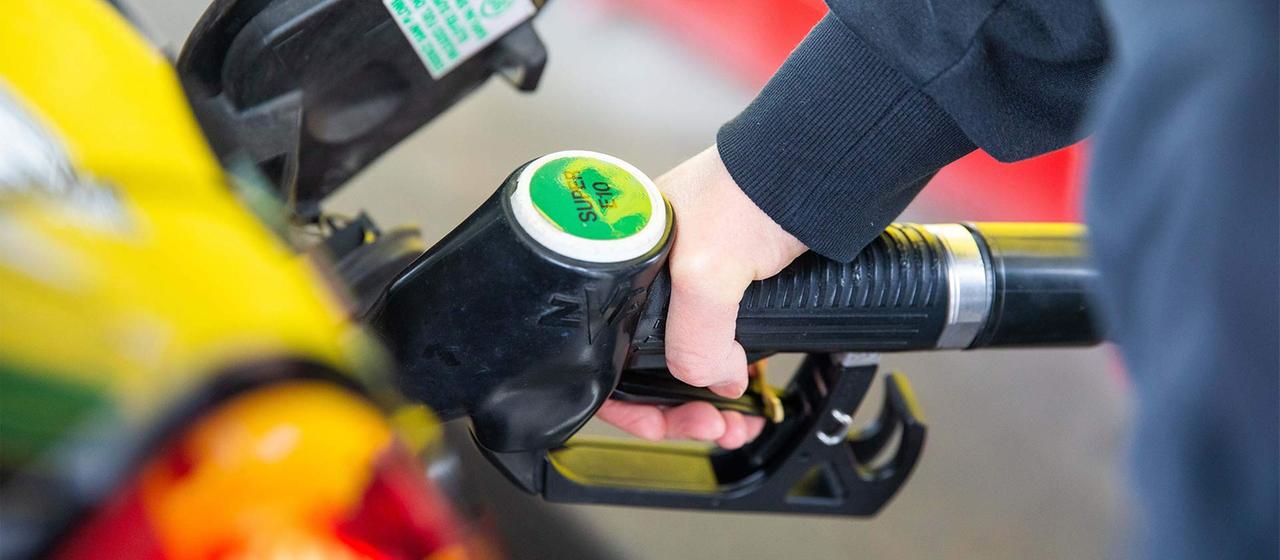 Eine Zapfpistole steckt im Tankstutzen eines Autos.