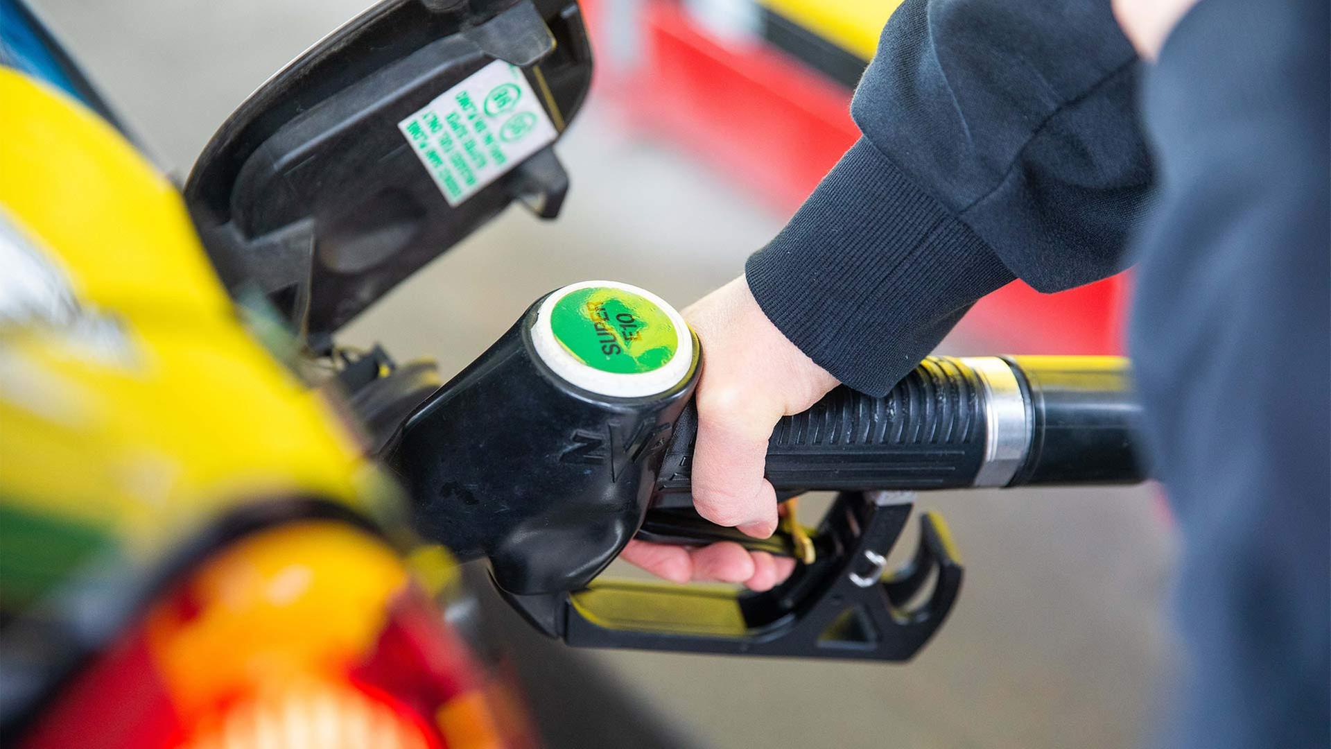 Eine Zapfpistole steckt im Tankstutzen eines Autos. | picture alliance / Fotostand