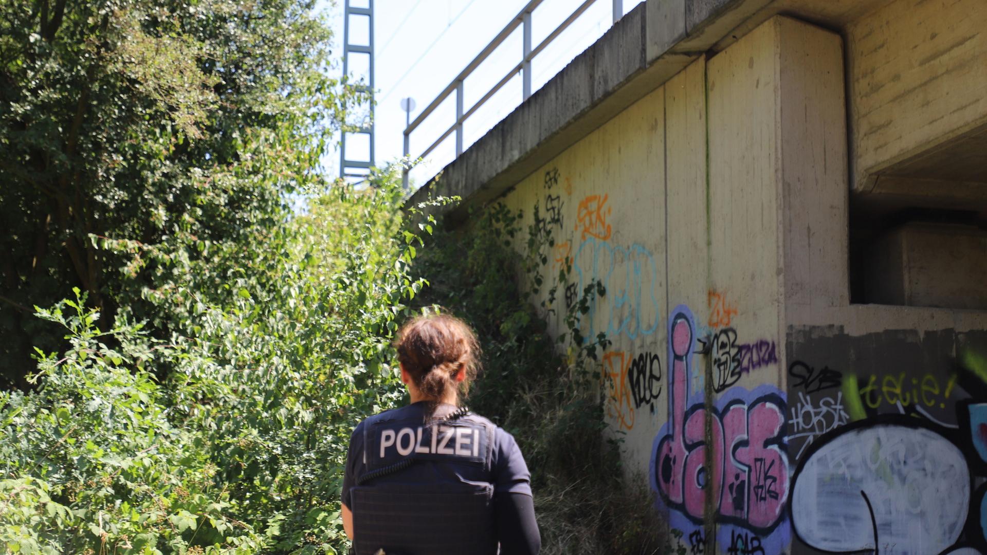 Eine Polizistin steht unter einer Brücke an einer Bahnstrecke bei Leverkusen. | Sascha Thelen/dpa