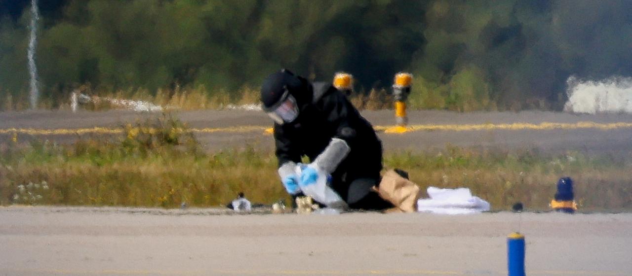 Ein Polizist in Schutzkleidung ermittelt am Flughafen Leipzig/Halle