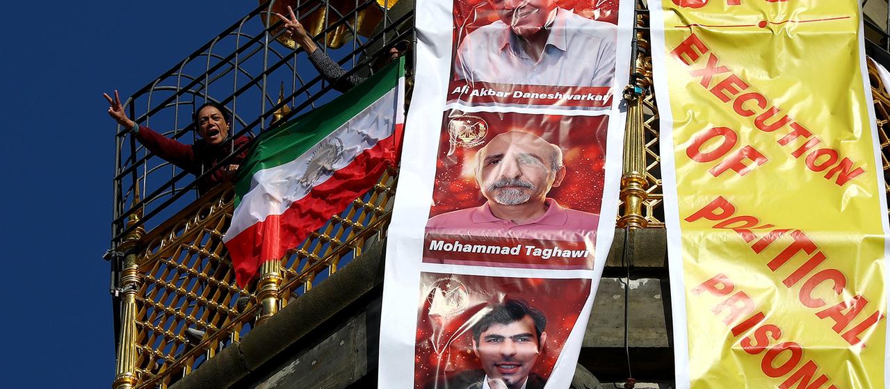 Menschen entrollen auf der Siegessäule in Berlin ein Transparent mit der Aufschrift "Stoppt die Hinrichtung politischer Gefangener im Iran!".