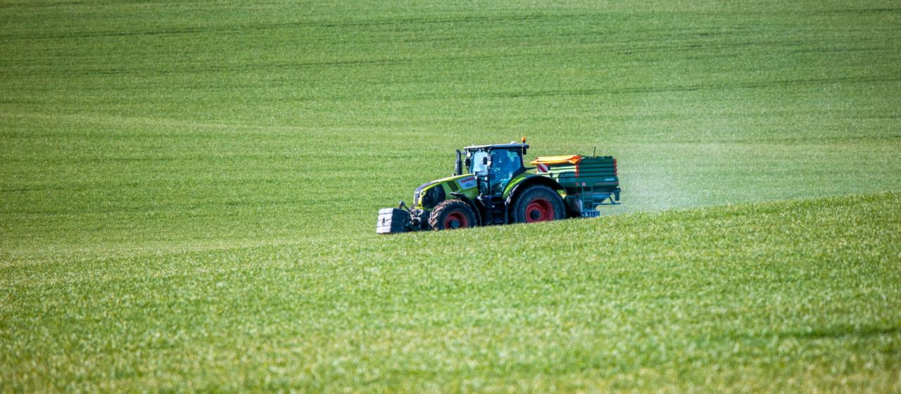 Ein Traktor verteilt Dünger auf einem Feld.