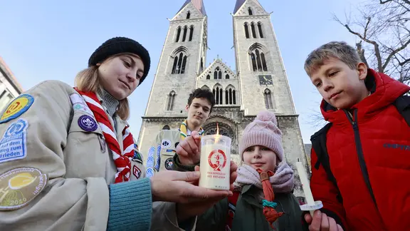 Pfadfinder nehmen vor dem Dom St. Sixtus und St. Stephanus das Friedenslicht aus Bethlehem in Empfang.