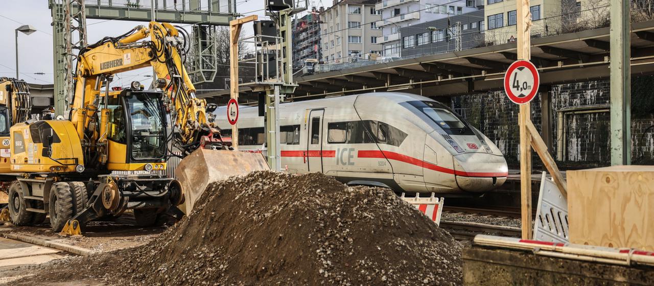 Ein ICE fährt in Wuppertal an einem Bagger vorbei, der auf seinen Einsatz wartet