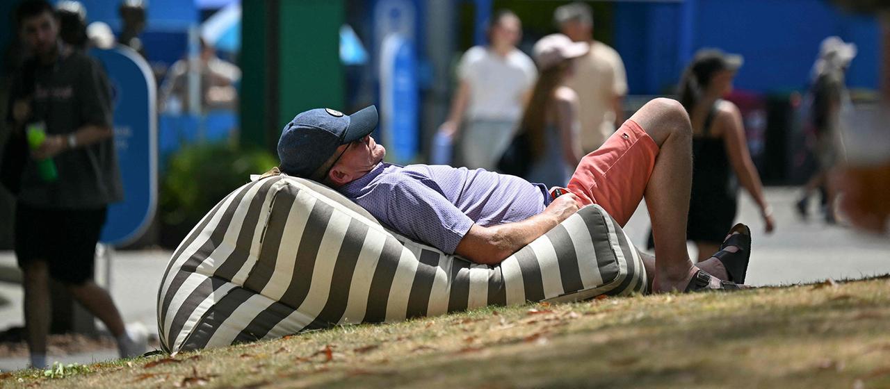 Ein Mann liegt bei sonnigem Wetter auf einem gestreiften Sitzsack im Freien.