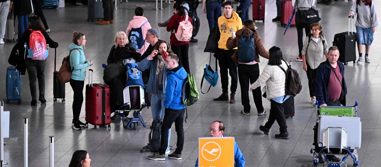 Fluggäste stehen nahe den Lufthansa-Schaltern am Flughafen Frankfurt