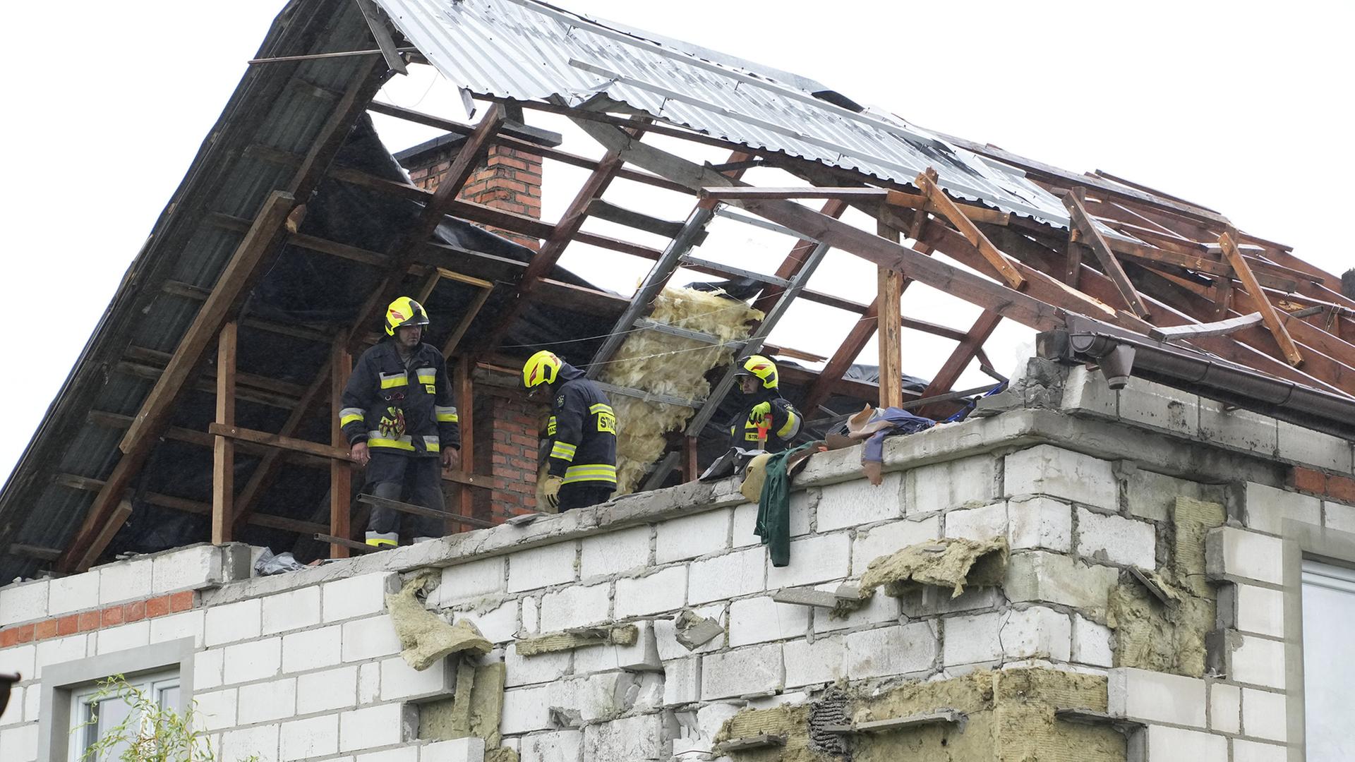 Feuerwehrleute arbeiten auf dem Dachboden eines zerstörten Hauses in Wyryki (Polen). | AP