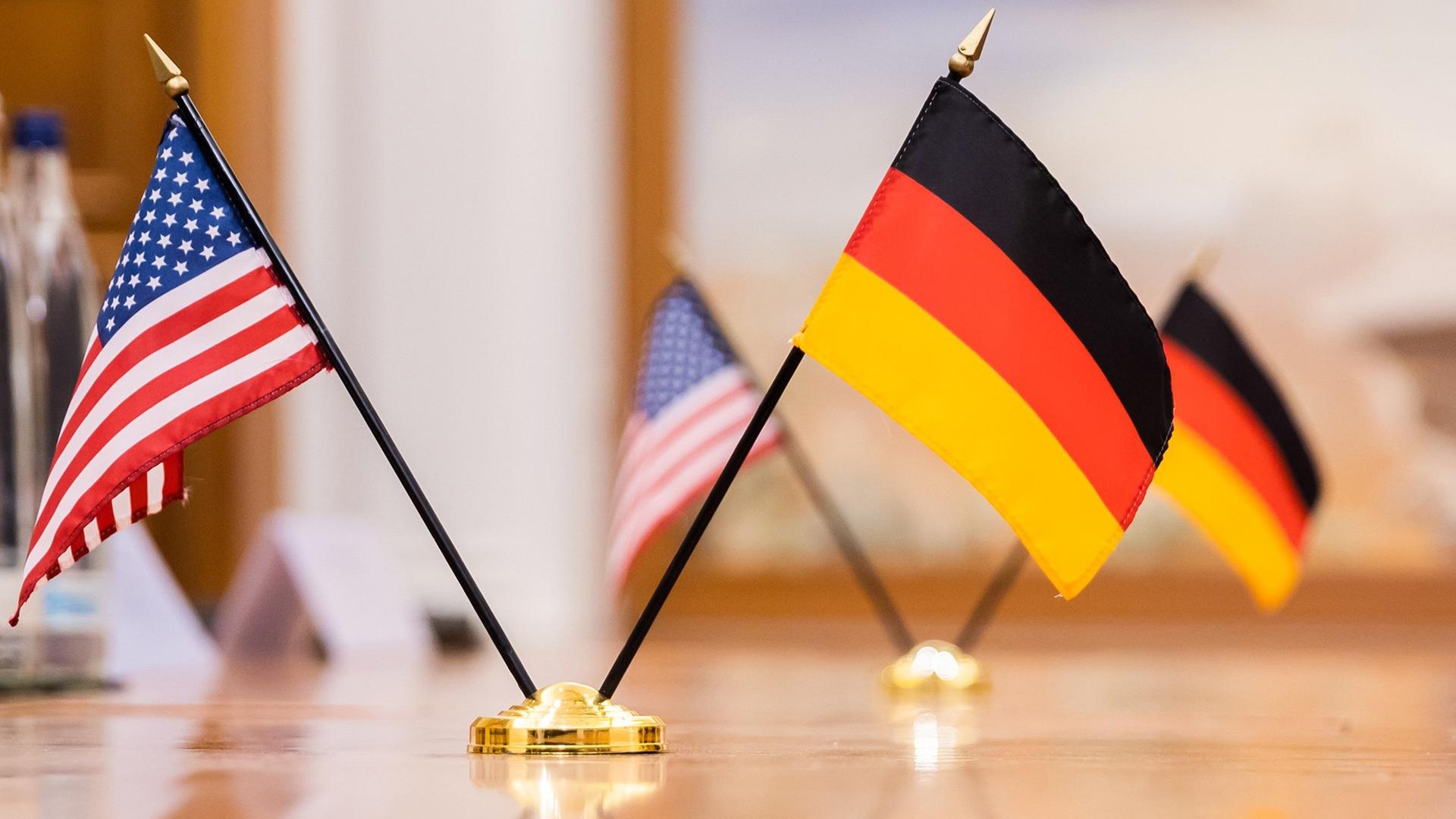 Kleine Flaggen der USA und Deutschlands stehen auf einem Tisch | picture alliance/dpa