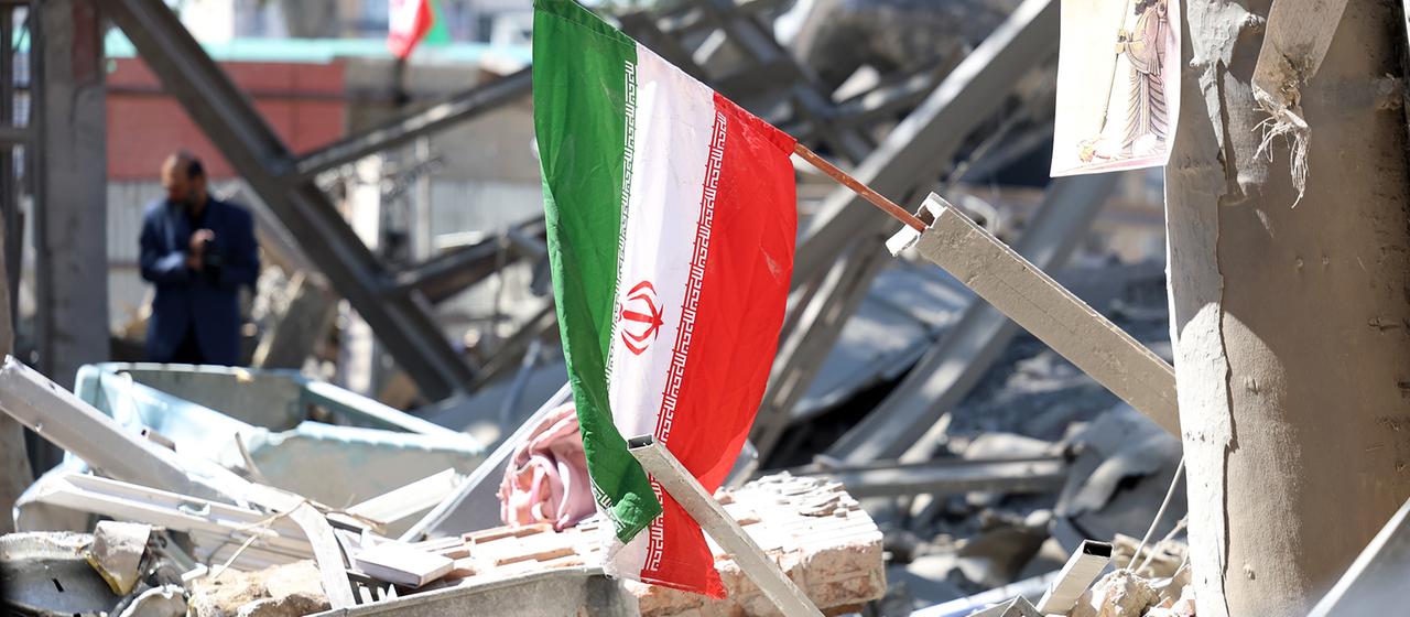 Eine iranische Nationalflagge hängt an Trümmern eines beschädigten Gebäudes der Sharif-Universität in Teheran.