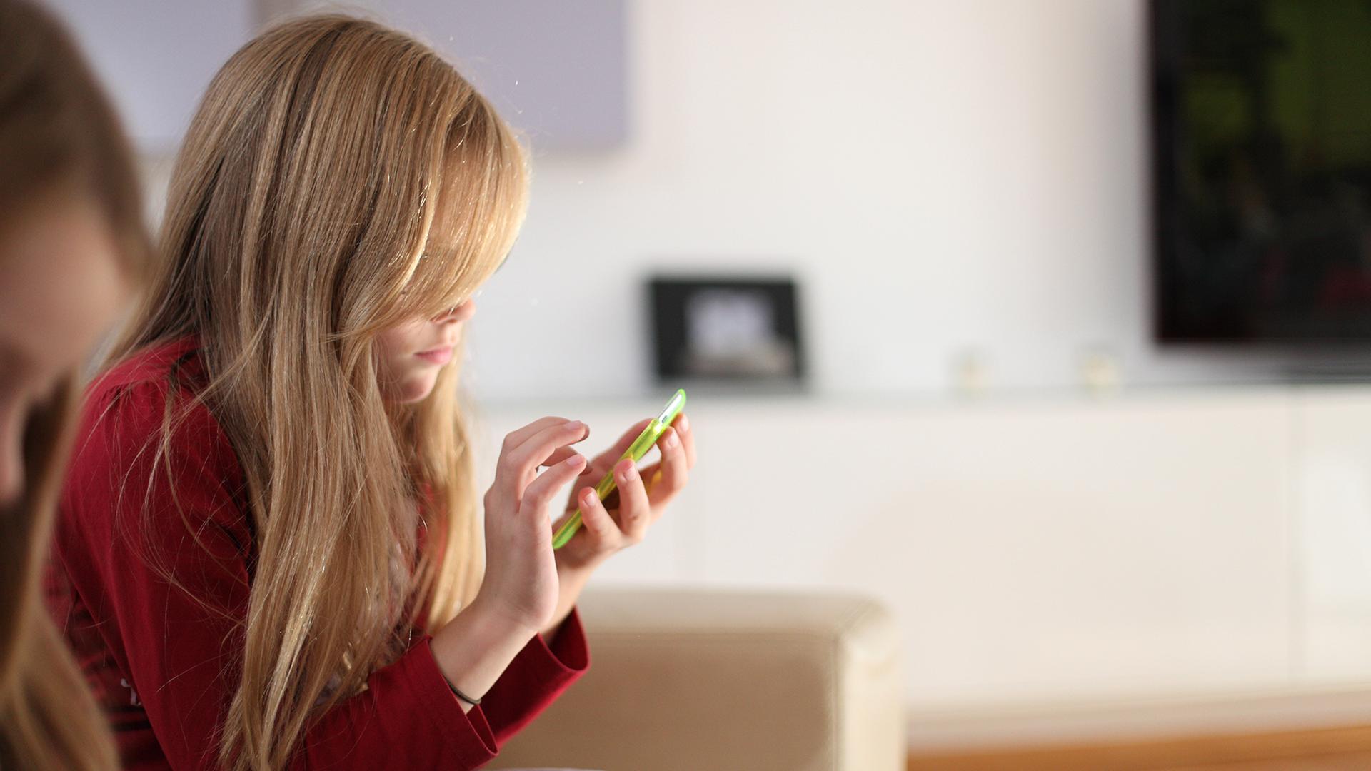 Ein Mädchen hält ein Handy in ihren Händen. | ARD-aktuell/ Lotz