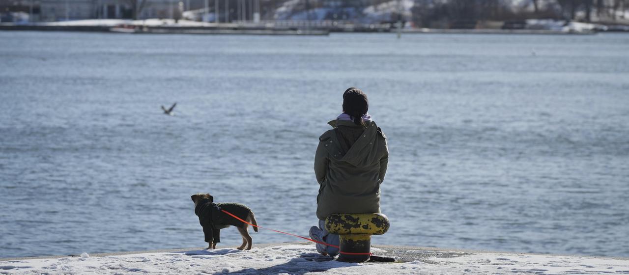 Eine Frau genießt den sonnigen und frostigen Tag am Ufer des Südhafens in Helsinki (Finnland).