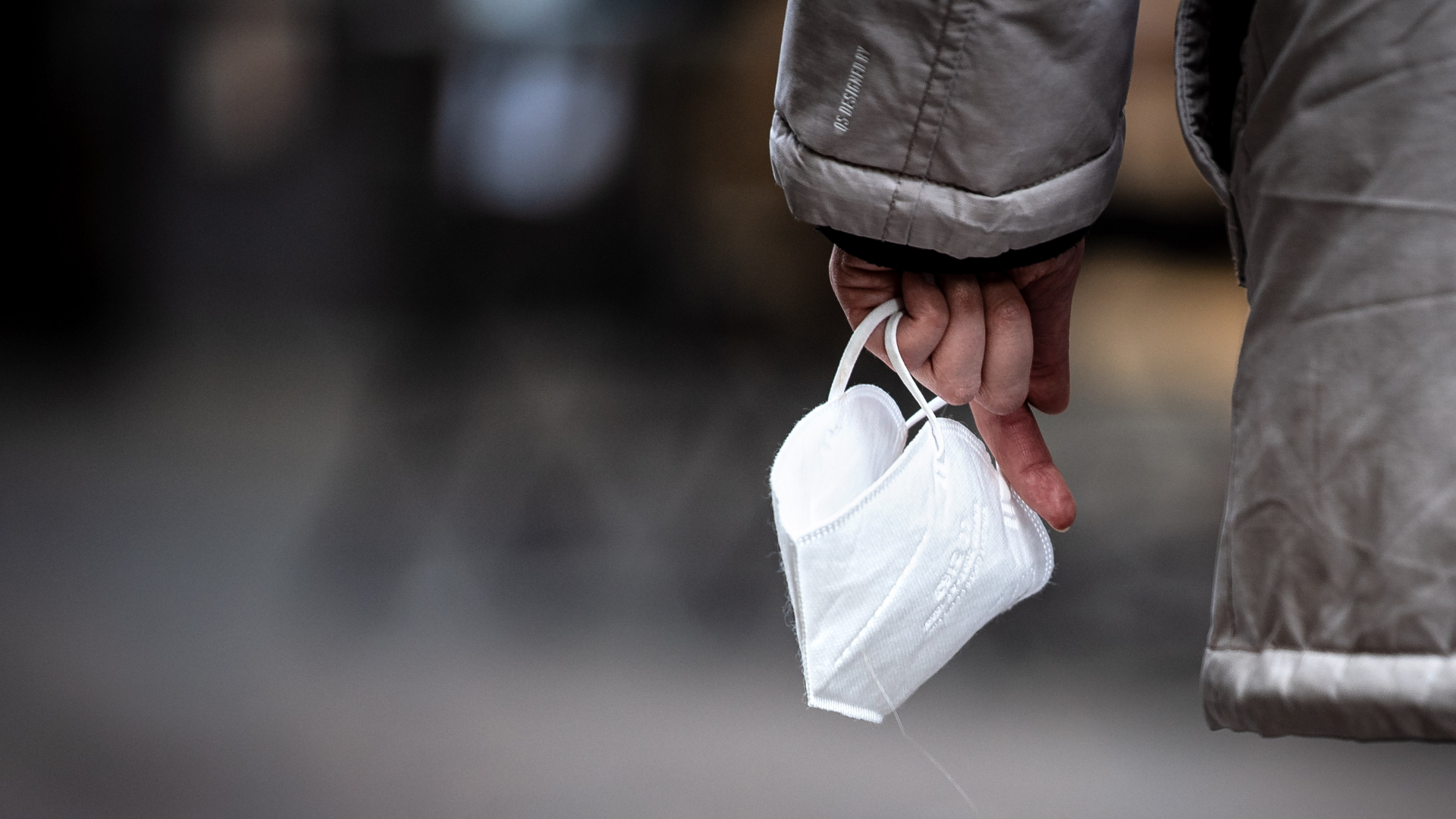 Eine Passantin hält eine FFP-2 Maske in der Hand.