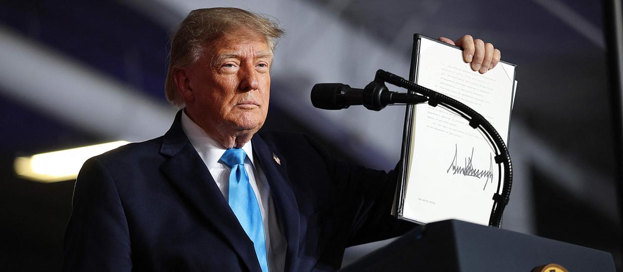 Donald Trump hebt ein von ihm unterzeichnetes Dekret in die Höhe.