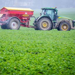 Ein Traktor verteilt Dünger auf einem Feld.