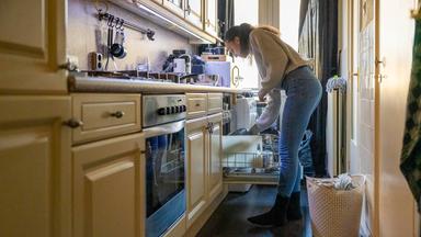 Eine Frau räumt in einer schmalen Küche den Geschirrspüler ein