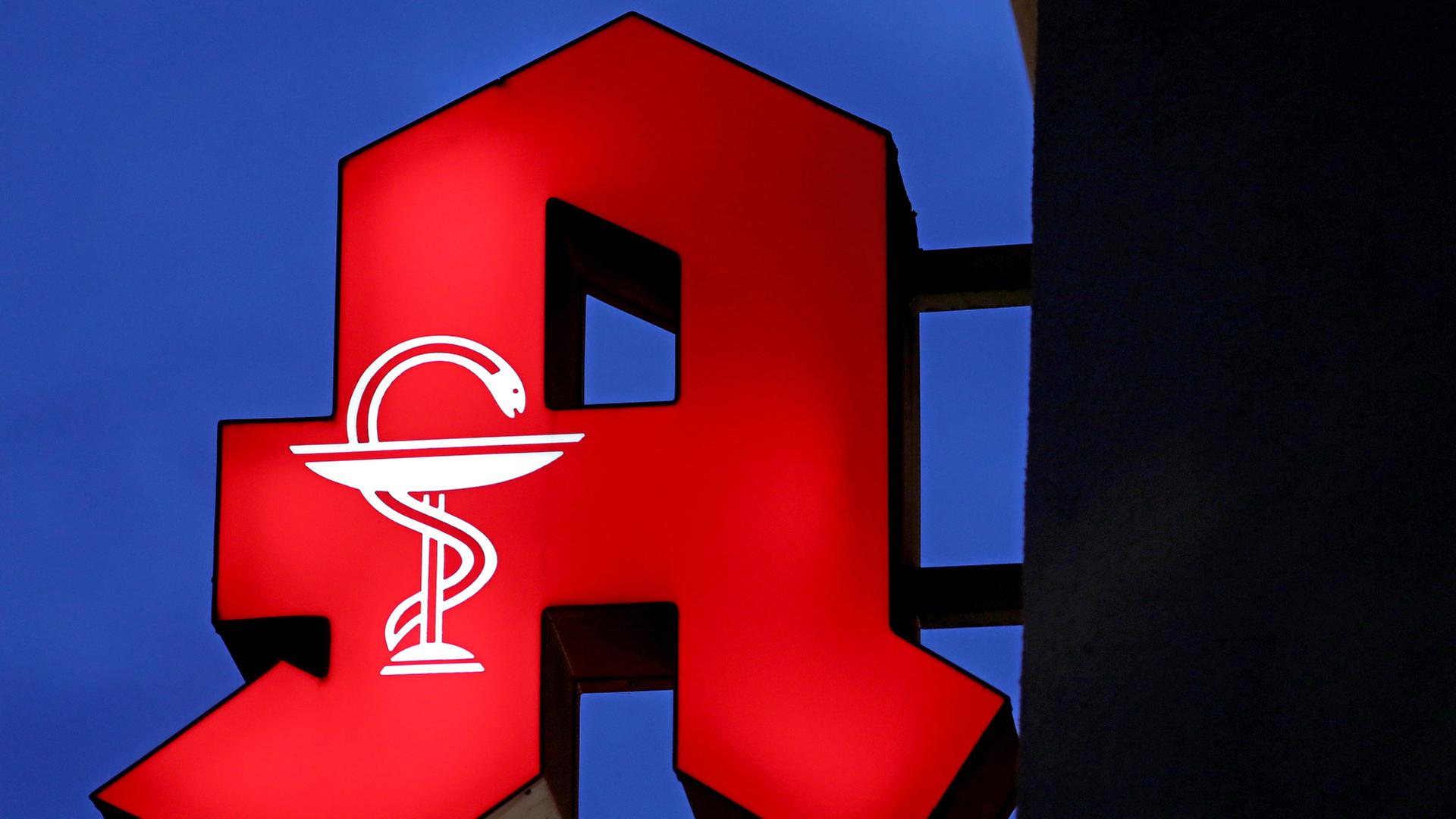 Das Apotheken-Logo leuchtet an einer Apotheke. | dpa