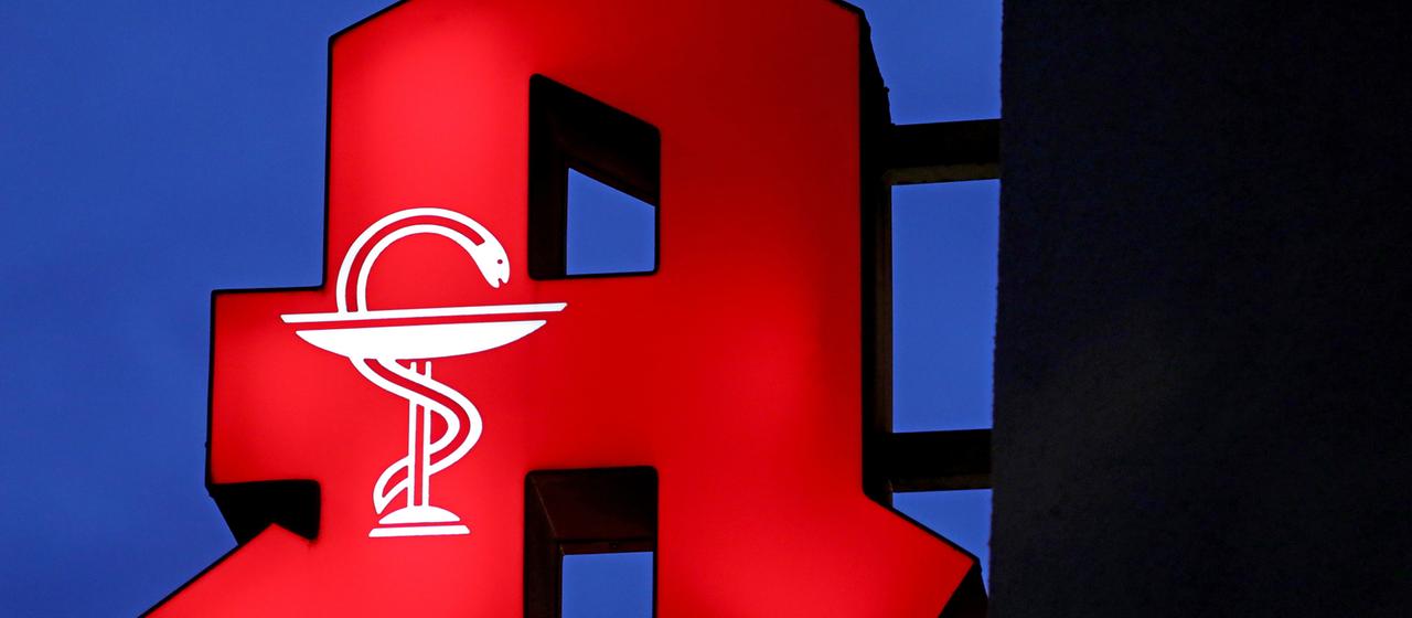 Das Apotheken-Logo leuchtet an einer Apotheke.