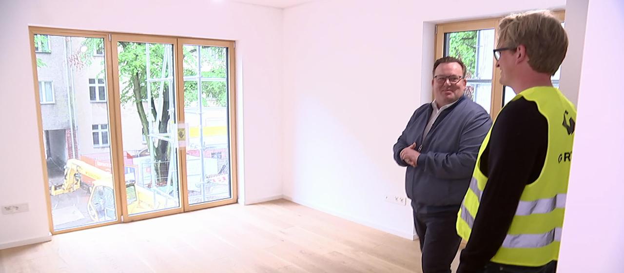 Zwei Menschen begehen eine leerstehende Wohnung.