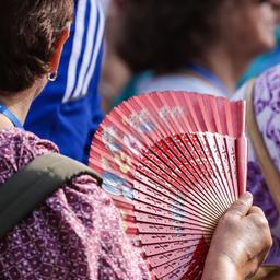Eine Touristin wedelt sich bei heißem Sommerwetter mit einem Fächer Luft zu.
