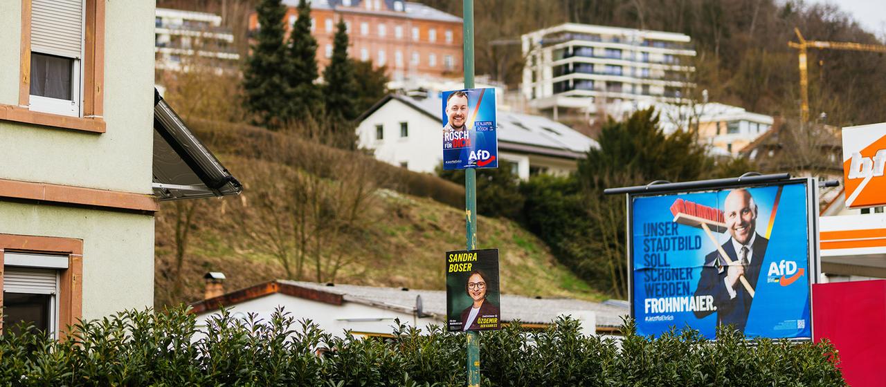 Wahlplakate der AfD sowie der Grünen hängen im Vorfeld der Landtagswahl an einem Laternenpfahl sowie auf einer Plakatwand in Lahr. 