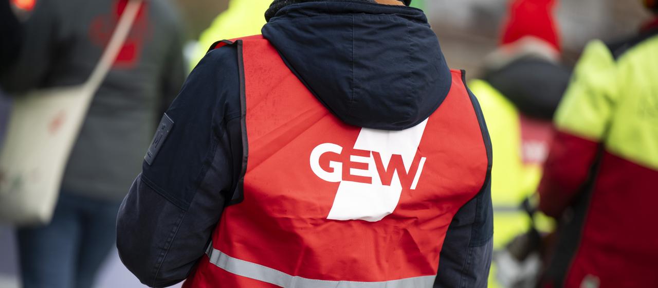 Ein Teilnehmer der Demonstration trägt eine Warnweste mit dem Logo der Gewerkschaft Erziehung und Wissenschaft (GEW) (Archivbild).