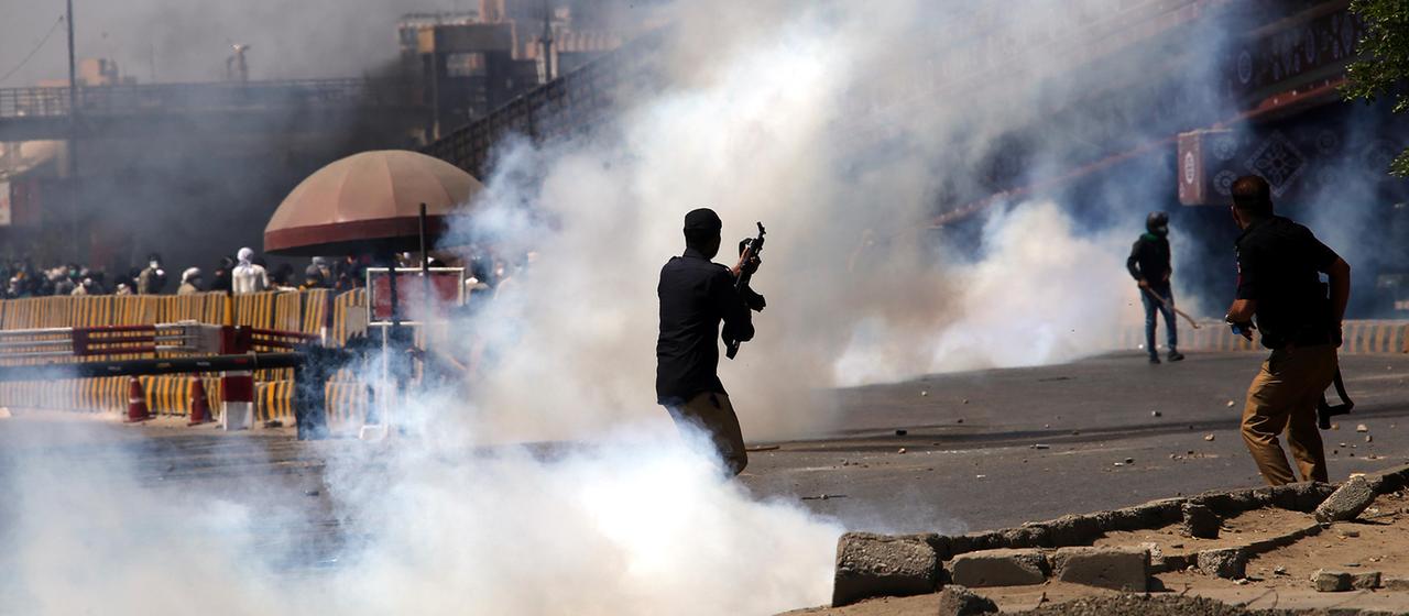 Rauch und bewaffnete Menschen bei einer Demonstration in der Nähe des US-Konsulats.