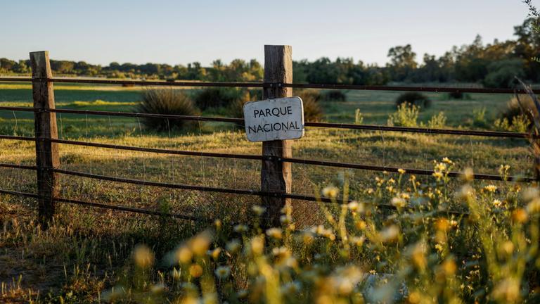 An einem Zaun im Donana-Nationalpark ist ein Nationalpark-Plakat angebracht