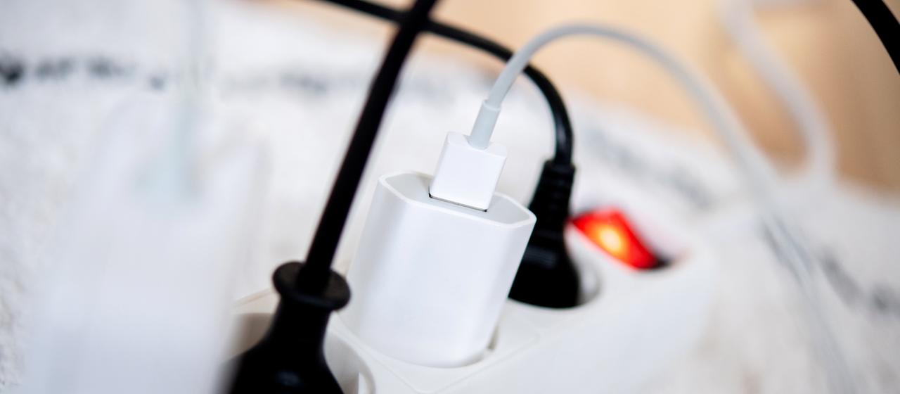 Die Netzstecker mehrerer Elektrogeräte stecken in einer Steckdosenleiste in einem Wohnzimmer.