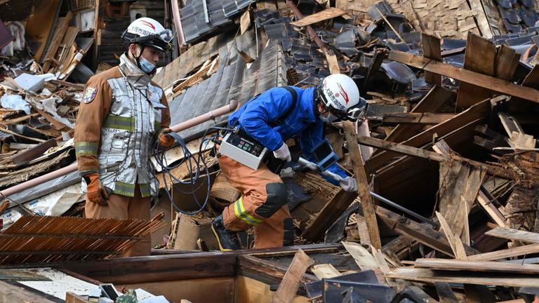 Einsatzkräfte suchen in den Trümmern eines eingestürzten Hauses in der Stadt Wajima.