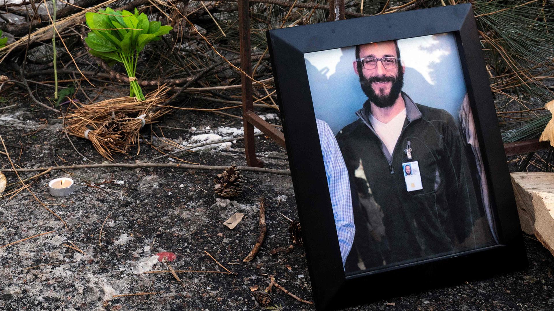 Ein gerahmtes Foto von Alex Pretti liegt neben einer brennenden Kerze auf dem Boden. | AFP