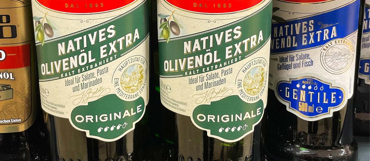 Flaschen mit Olivenöl in einem Supermarktregal.